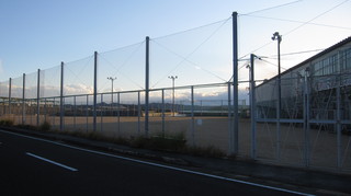 高い防護ネットに囲まれている屋外グラウンドの写真