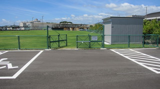 芝生の屋外グラウンドに出入り口のフェンスが設置されている写真