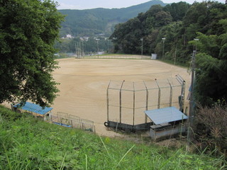 山に囲まれている土のグラウンドの写真