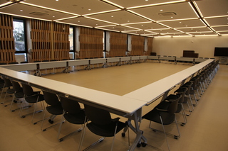 長机と椅子がロの字型に並べれている広い室内の写真