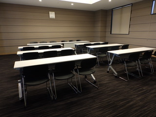 長机1つに椅子3脚が6セット並んだ室内の写真