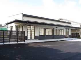 白い壁で扉が二か所ある一階建ての建物の外観写真