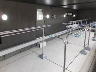 竿が吊るされた物干し台が複数設置された部屋の写真