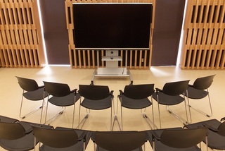 大型テレビの前に椅子が2段のアーチ状に並べられている写真