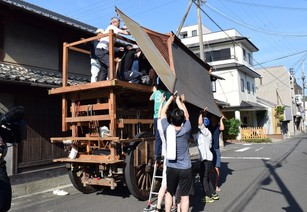 山車の屋根を取り付けている男性たちの写真