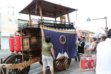 山車に幕を取り付けている人たちの写真