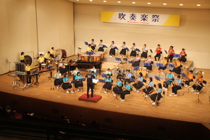 大ホールの舞台上で各々の楽器を手に演奏する学生達の写真