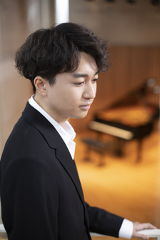 右下に視線を落としているスーツ姿の男性の写真