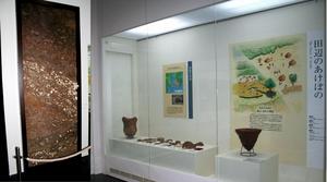 説明パネルと土器や小さい出土品が並べられた展示の写真