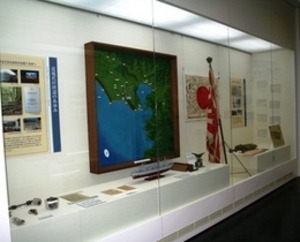 大きな地図と実物資料が並べられた展示の写真