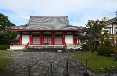 石畳の道の先にある瓦屋根の赤い和風の建物の写真
