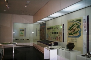 説明パネルと出土品が壁にL字に並べられた展示の写真