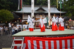 神社の敷地内に設けられた舞台で舞う巫女たちの写真