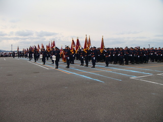 広い会場で消防団員たちが隊列を組んで整列している全体の写真