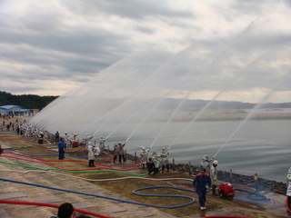 海岸で消防団員たちが一斉に放水している全体の写真