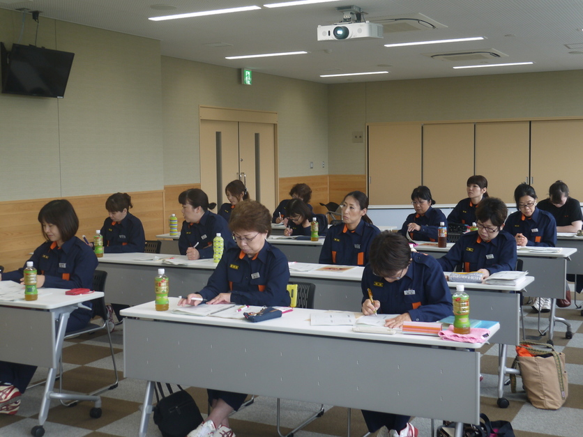 研修室で防火服を着た団員たちが着席して講義を受けている写真