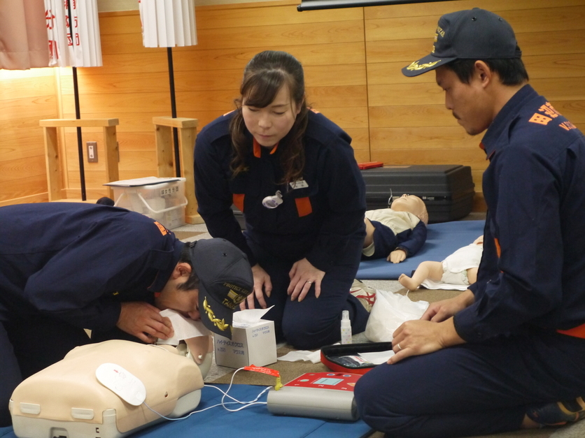 研修室で消防団員たちが人形を使って心肺蘇生の実技訓練をしている写真