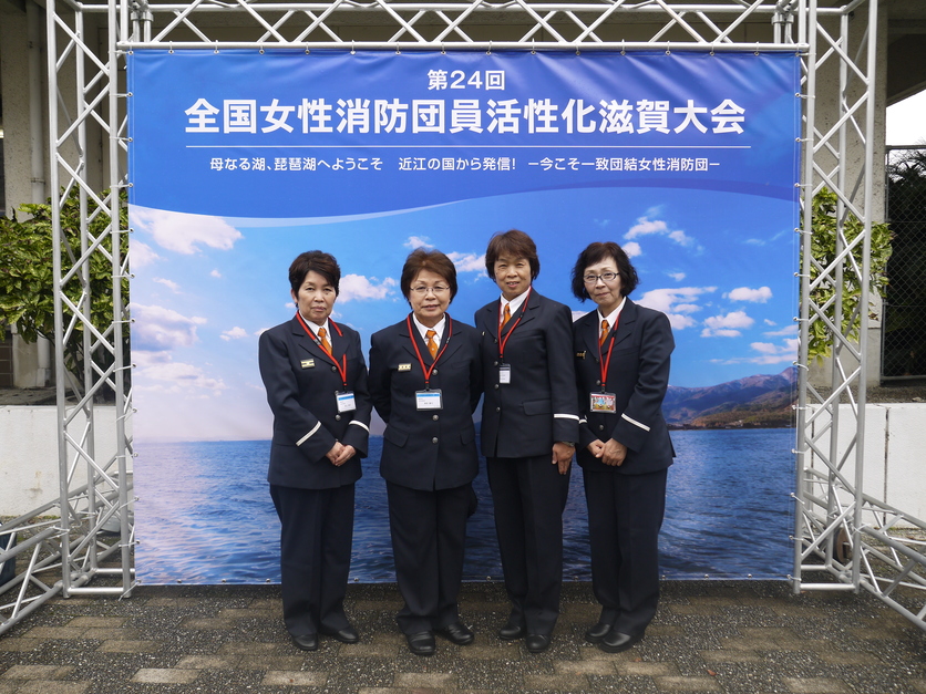 フォトスポットの前で制服姿の女性消防団員たちが並んで記念撮影している写真