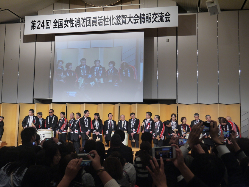 大会会場の壇上で各地の代表者が並んで紹介されている全体の写真