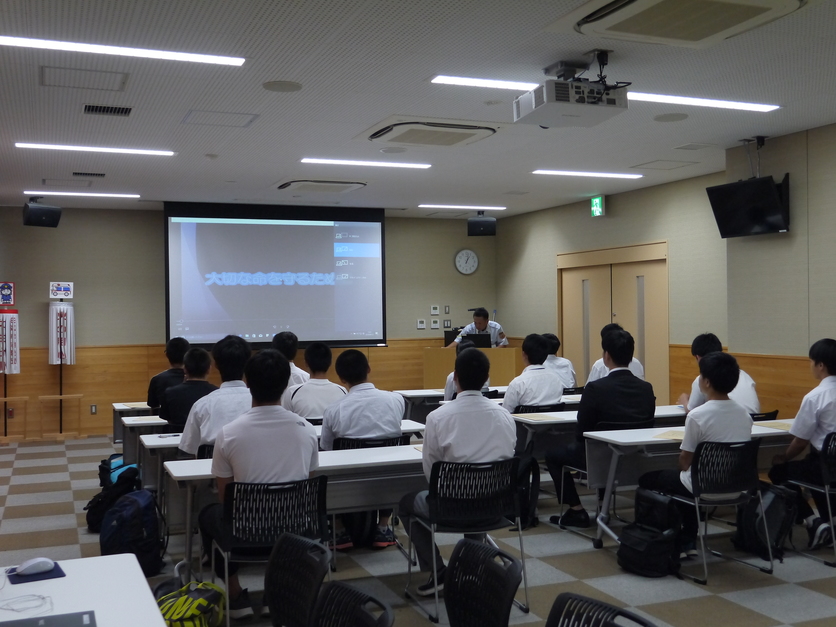 講義室で学生たちが着席して防災講習を受けている様子を後ろから写した写真