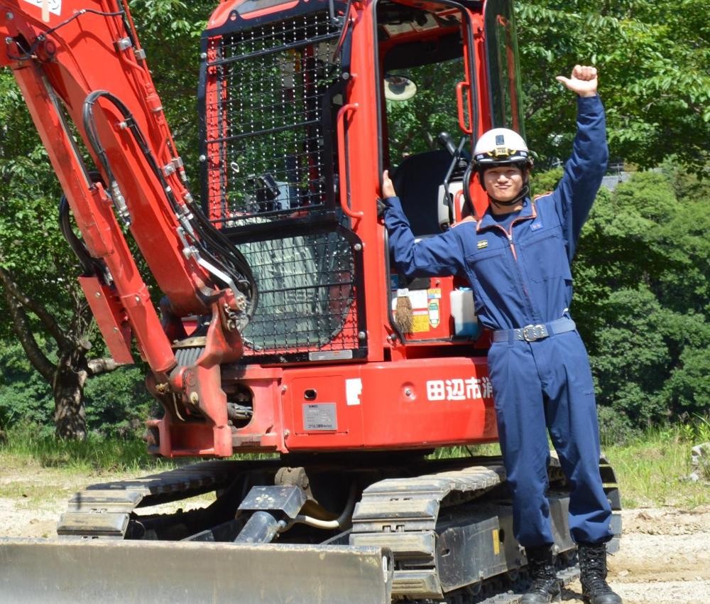 重機隊に所属する田辺市消防職員が重機の前で立っている写真