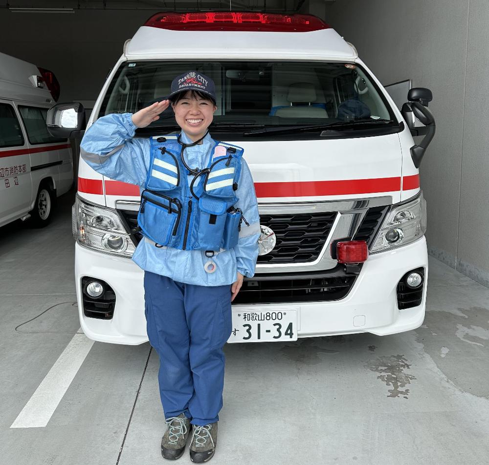 救急車の前で敬礼する救急隊員の写真