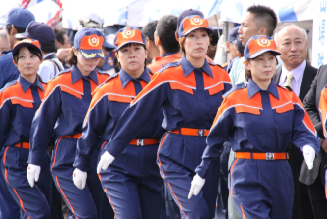 会場で制服姿の女性消防団員たちが隊列を組んで行進している正面からの写真