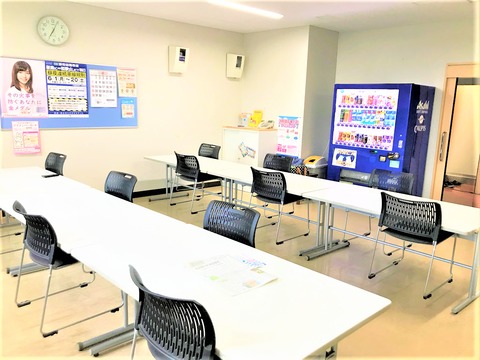 自販機と長机と椅子が並んだ待合室全体の様子を写した写真