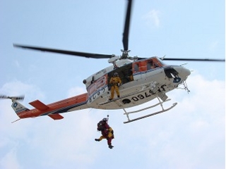 ヘリコプターから二人の消防隊員がロープをつたって降下している写真