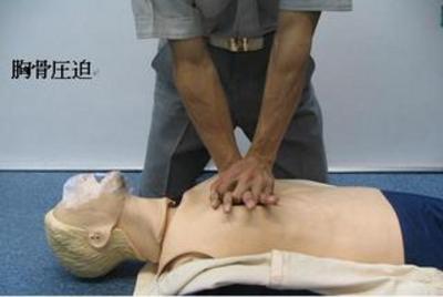 横たわっている人の胸骨を圧迫している男性の写真
