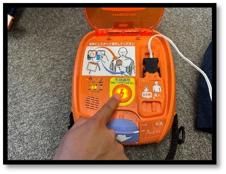 AEDのショックボタンを押している画像