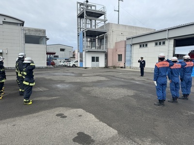 防火服や救助服に身を包んだ消防隊員たちが消防長に対して敬礼をしている写真