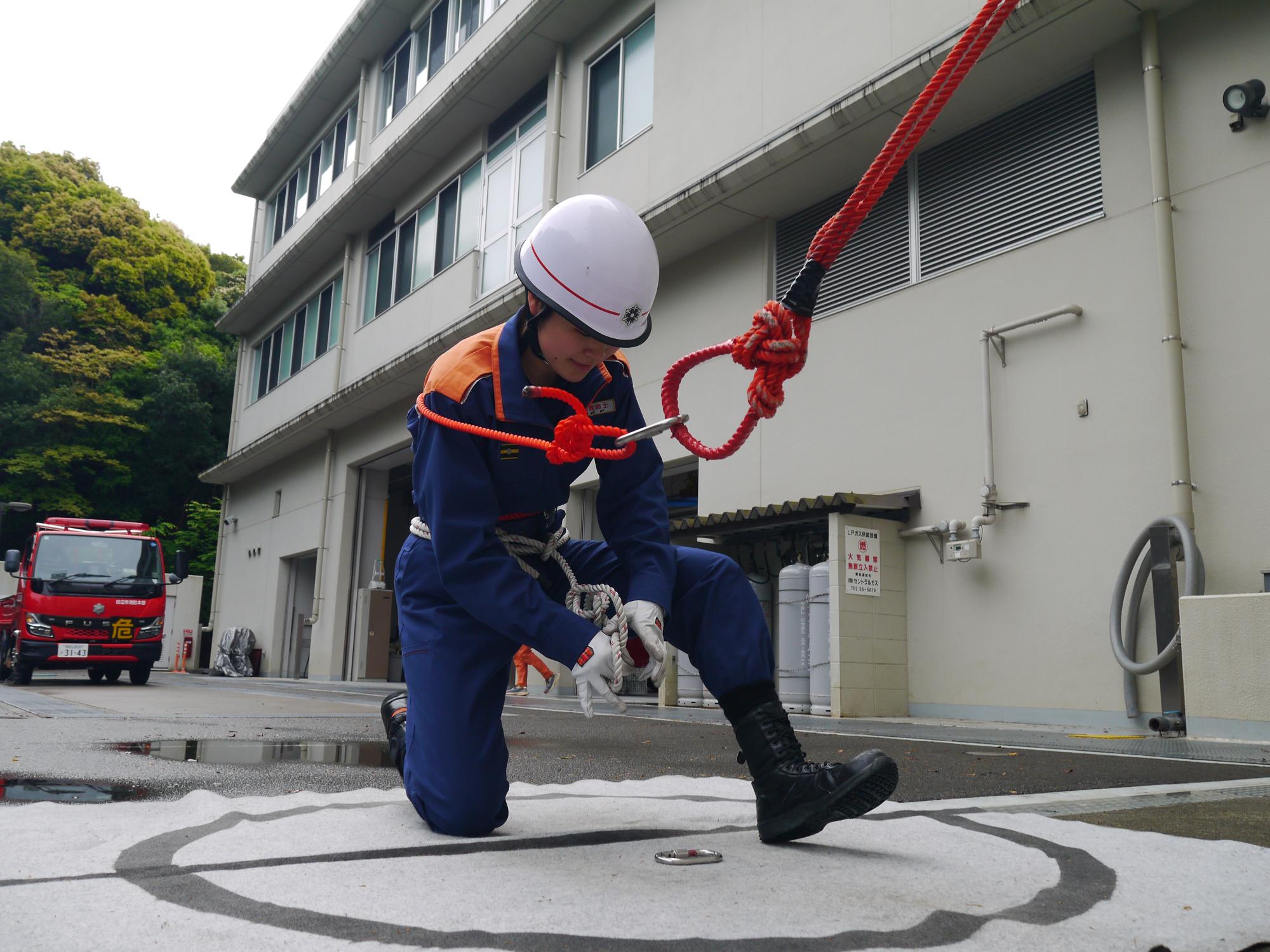 隊員がはしごを登るために自己確保用ロープを結索している画像