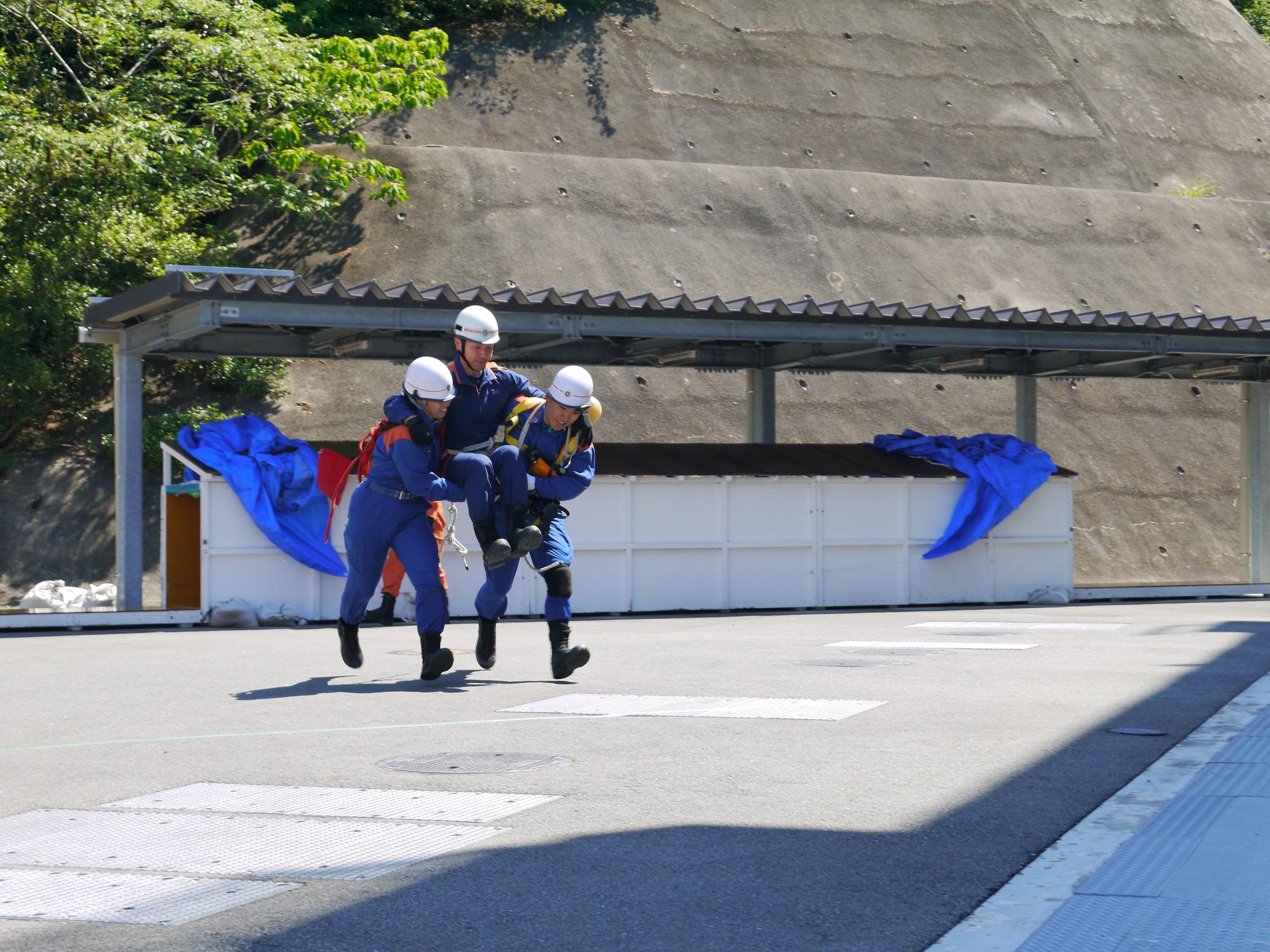 隊員2人が要救助者を抱えて搬送している画像