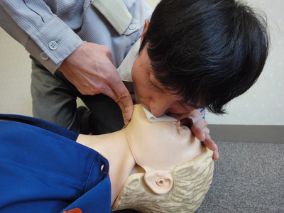 横たわっている人にマウストゥーマウスで人工呼吸を行っている男性の写真