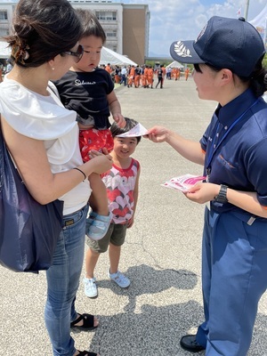 消防員から個包装タイプの種ぬき梅干しを受け取っている親子連れの写真