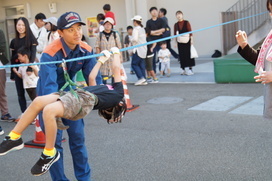 水平に渡されたロープに子どもが体を平行にして吊るされている写真