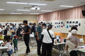 写真が展示されている室内に多くの人が集まっている写真