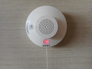 ランプが赤く光り作動している、壁に設置された火災報知器の写真