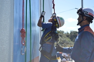 ヘルメットをかぶった子どもが上から延びたロープに手をかけている写真