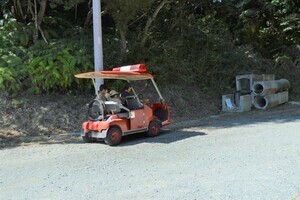 窓やドアのない小さな赤い車が道の路肩に停められている写真