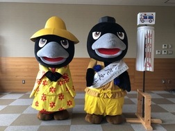 こちらを向いて横に並んで立つ、カラスのキャラクター着ぐるみを着た人物2人の写真