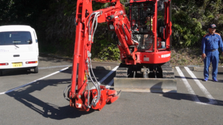 駐車場に停められた赤色のクレーン車がクレーンの先を地面に下ろしている写真