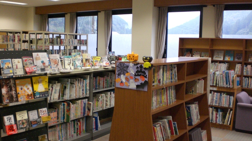 沢山の本が入っている本棚にハロウィンの飾り物が飾り付けられている写真