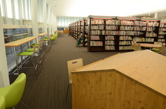 背の高い本棚と窓に沿って椅子と机が並んでいるエリア全体の写真