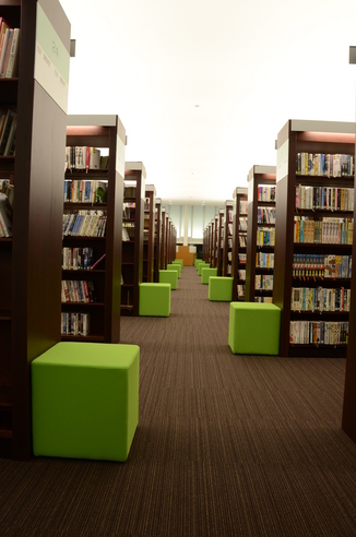 多くの書籍が蔵書されている背が高い本棚が並んでいる図書館内の写真