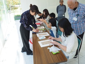 ワークショップで講師から粘土での山水画の作り方を学んでいる子どもたちの写真