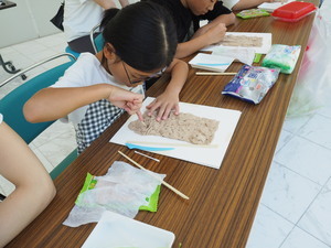指先を使い粘土の山水画作りに集中して取り組む子どもの写真