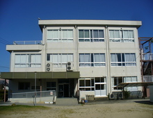 青空のもと建っている白い壁の建物の外観写真