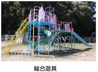 遠くに木々が見えて水色と黄色を用いた総合遊具の写真